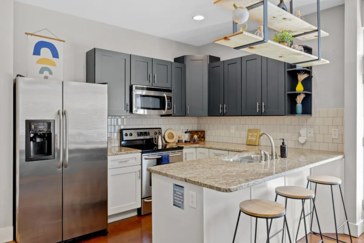 A modern, functional kitchen with gleaming granite countertops, stainless steel appliances, and open shelving. The space is designed for both cooking and socializing, making it ideal for preparing group meals before or after exploring nearby attractions. The layout encourages gathering—perfect for multi-family groups or friends traveling together.