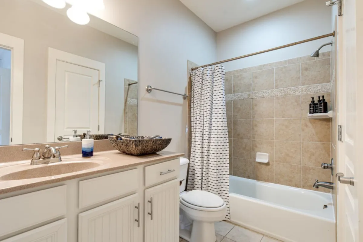 A fresh and inviting bathroom featuring a double sink vanity, a large framed mirror, and a bathtub with shower. The neutral tones and clean lines create a soothing environment for self-care or a relaxing bath at the end of the day.